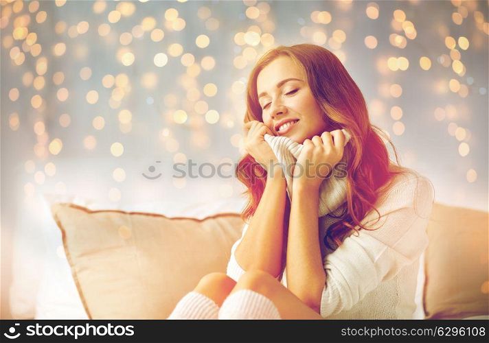 christmas, winter, comfort and people concept - happy young woman in warm pullover at home. happy young woman in warm pullover at home