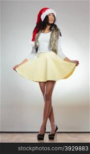 Christmas winter happiness concept. Full length of fashion woman, girl mixed race wearing santa helper hat on gray