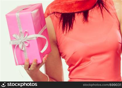 Christmas winter happiness concept. Girl mixed race woman wearing red dress santa helper hat holding pink present gift box filtered photo