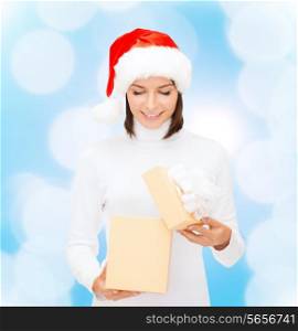 christmas, winter, happiness, holidays and people concept - smiling woman in santa helper hat opening gift box over blue lights background