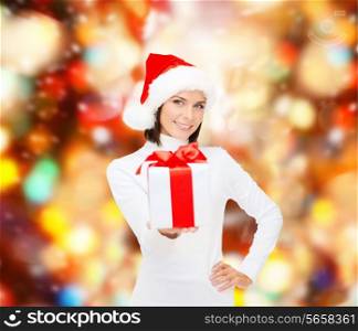 christmas, winter, happiness, holidays and people concept - smiling woman in santa helper hat with gift box over red lights background
