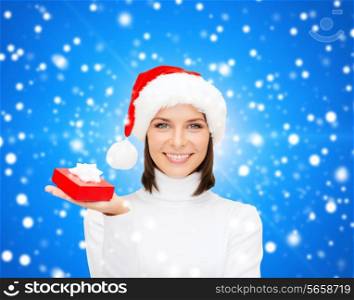 christmas, winter, happiness, holidays and people concept - smiling woman in santa helper hat with small red gift box over blue snowy background