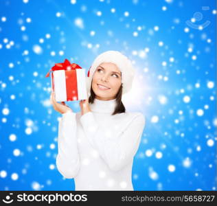 christmas, winter, happiness, holidays and people concept - smiling woman in santa helper hat with gift box over blue snowy background