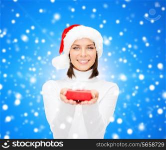 christmas, winter, happiness, holidays and people concept - smiling woman in santa helper hat with small red gift box over blue snowy background
