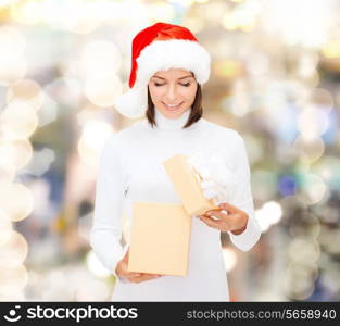christmas, winter, happiness, holidays and people concept - smiling woman in santa helper hat opening gift box over lights background
