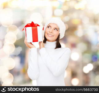 christmas, winter, happiness, holidays and people concept - smiling woman in santa helper hat with gift box over lights background