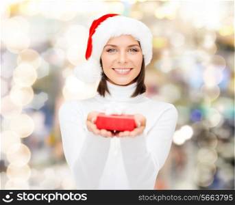 christmas, winter, happiness, holidays and people concept - smiling woman in santa helper hat with small red gift box over lights background
