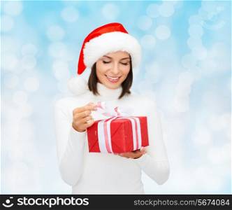 christmas, winter, happiness, holidays and people concept - smiling woman in santa helper hat with gift box over blue lights background