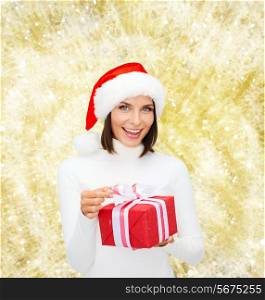 christmas, winter, happiness, holidays and people concept - smiling woman in santa helper hat with gift box over yellow lights background