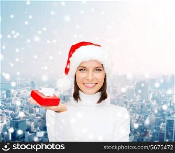 christmas, winter, happiness, holidays and people concept - smiling woman in santa helper hat with small red gift box over snowy city background
