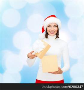 christmas, winter, happiness, holidays and people concept - smiling woman in santa helper hat with gift box over blue lights background