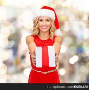 christmas, winter, happiness, holidays and people concept- smiling woman in santa helper hat with gift box over lights background
