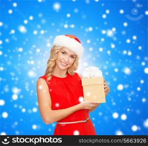 christmas, winter, happiness, holidays and people concept- smiling woman in santa helper hat with gift box over blue snowy background