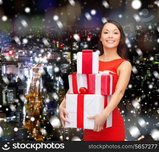 christmas, winter, happiness, holidays and people concept- smiling woman with gift boxes over snowy night city background