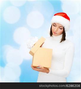 christmas, winter, happiness, holidays and people concept - woman in santa helper hat with gift box over blue lights background