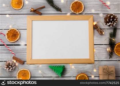 christmas, winter holidays and celebration concept - white magnetic board, electric garland lights and decorations on grey shabby boards background. white board, garland and christmas decorations