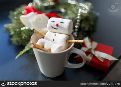 christmas, winter holidays and leisure concept - close up of marshmallow snowman taking bath in cup of coffee. marshmallow snowman in cup of coffee on christmas