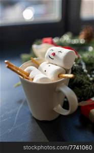christmas, winter holidays and leisure concept - close up of marshmallow snowman taking bath in cup of coffee. marshmallow snowman in cup of coffee on christmas