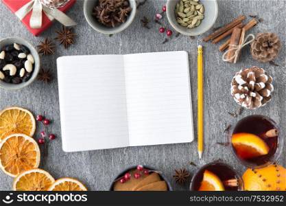 christmas, winter holidays and new start concept - notebook with pencil, hot mulled wine and aromatic spices on grey background. notebook, pencil and hot mulled wine on christmas
