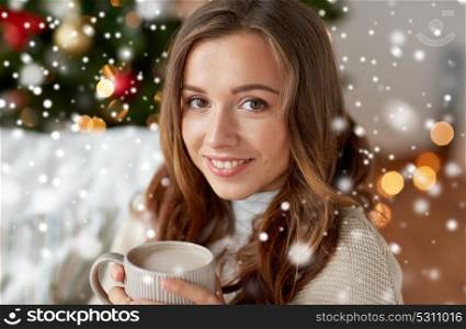 christmas, winter holidays and people concept - happy young woman with cup of coffee or cocoa drink at home over snow. happy woman drinking cocoa at home for christmas