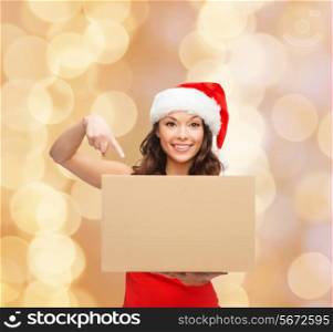 christmas, winter, holidays, delivery and people concept - smiling woman in santa helper hat with parcel box over beige lights background