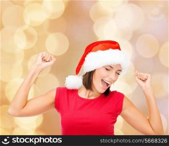 christmas, winter, holidays, happiness and people concept - smiling woman in santa helper hat and blank red shirt over beige lights background