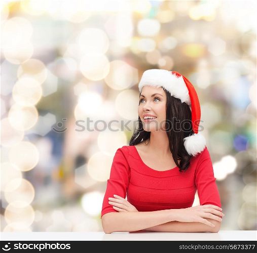 christmas, winter, holidays, happiness and people concept - smiling woman in santa helper hat over lights background