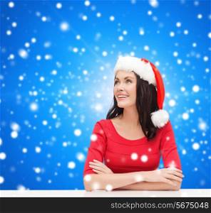 christmas, winter, holidays, happiness and people concept - smiling woman in santa helper hat over blue snowy background