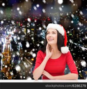 christmas, winter, holidays, happiness and people concept - smiling woman in santa helper hat over snowy night city background