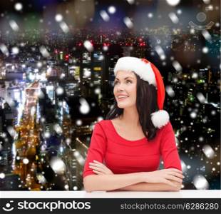 christmas, winter, holidays, happiness and people concept - smiling woman in santa helper hat over snowy night city background