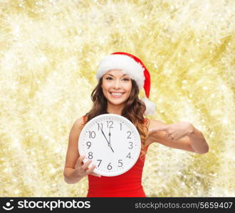 christmas, winter, holidays, time and people concept - smiling woman in santa helper hat and red dress with clock over yellow lights background