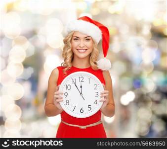 christmas, winter, holidays, time and people concept - smiling woman in santa helper hat and red dress with clock over lights background