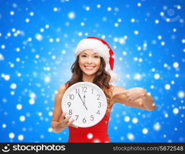 christmas, winter, holidays, time and people concept - smiling woman in santa helper hat and red dress with clock over blue snowing background