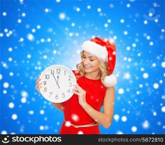 christmas, winter, holidays, time and people concept - smiling woman in santa helper hat and red dress with clock over blue snowing background