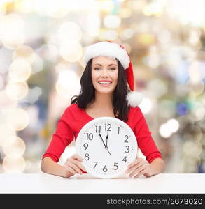 christmas, winter, holidays, time and people concept - smiling woman in santa helper hat and red dress with clock over lights background