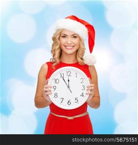 christmas, winter, holidays, time and people concept - smiling woman in santa helper hat and red dress with clock over blue lights background