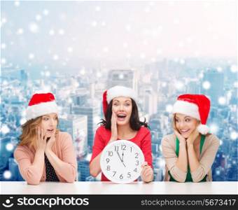 christmas, winter, holidays, time and people concept - smiling women in santa helper hats with clock over snowy city background