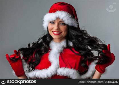 Christmas Woman in Santa Hat. Fashion Model with Makeup and Long Healthy Curly Hair. Christmas Woman in Santa Hat