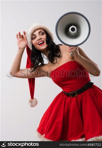 Christmas woman with a megaphone against a white background. Wearing Santa Claus red hat and dress