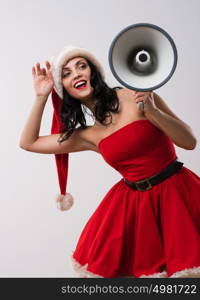 Christmas woman with a megaphone against a white background. Wearing Santa Claus red hat and dress