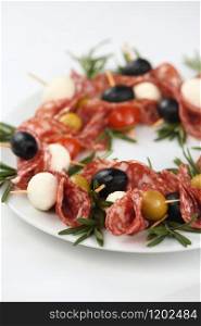 Christmas wreath - antipasto. Salami canapes with olives, baby mozzarella.