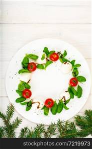 Christmas wreath caprese salad festive appetizer on a white plate. Studio Photo. Christmas wreath caprese salad festive appetizer on a white plat