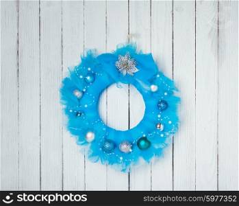 Christmas wreath from blue guipure on white wall. Christmas guipure wreath