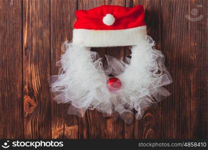 Christmas wreath like Santa head from lace and red bauble on the wooden door. Christmas wreath like Santa