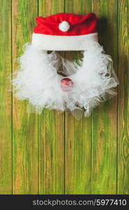 Christmas wreath like Santa head from lace and red bauble on the wooden door. Christmas wreath like Santa