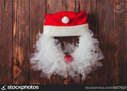 Christmas wreath like Santa head from lace and red bauble on the wooden door. Christmas wreath like Santa