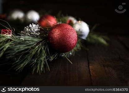 Christmas wreath of fir branches with Christmas decorations, pine cones and gifts on the brown background