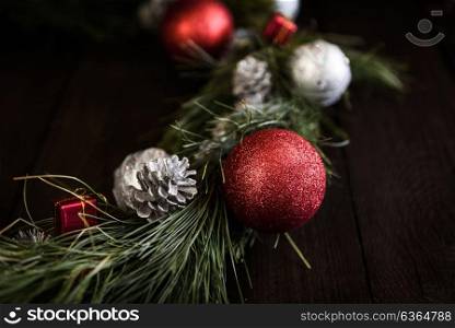 Christmas wreath of fir branches with Christmas decorations, pine cones and gifts on the brown background
