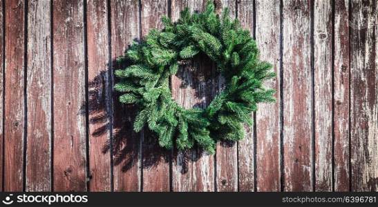 Christmas wreath on the shabby wooden wall. Christmas holiday background with copy space. Christmas wreath on the wall