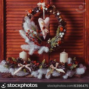 Christmas wreath on the wooden wall. Red and white elements, textile heart hangs. Red and white Christmas wreath